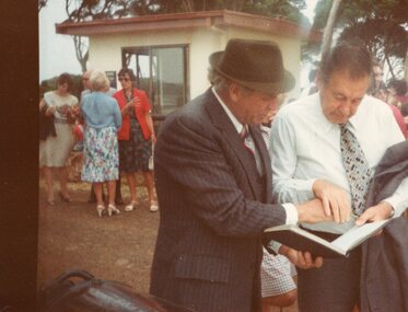 Photograph of two men looking at a book