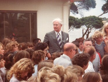 Photograph of man standing above a crowd