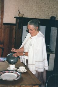Photograph of a woman pouring tea