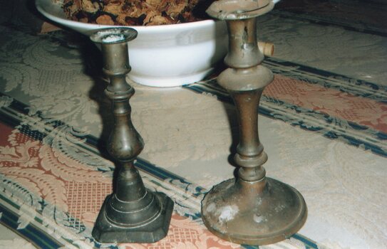 Taller brass candlestick on right.