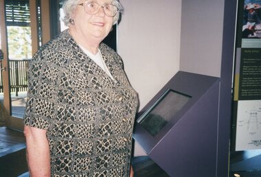Photograph of woman beside information terminal