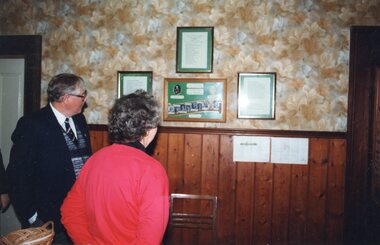 Photograph of two people looking at framed wall displays