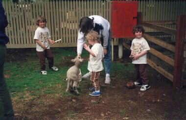 Photograph of four people and a lamb