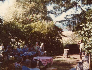 Photograph of people seated under a tree