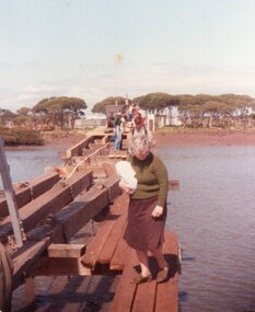 Photograph of woman walking on wooden bridge