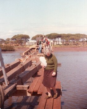 Photograph of woman walking on wooden bridge