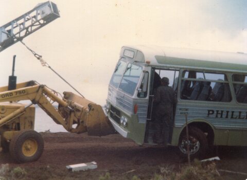 Photograph of bus being moved by a front loader