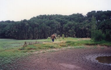 Photograph of man walking across a meadow
