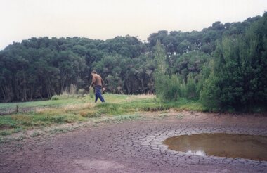 Photograph of man walking across a meadow
