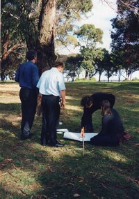 Photograph of four people gathered around paper