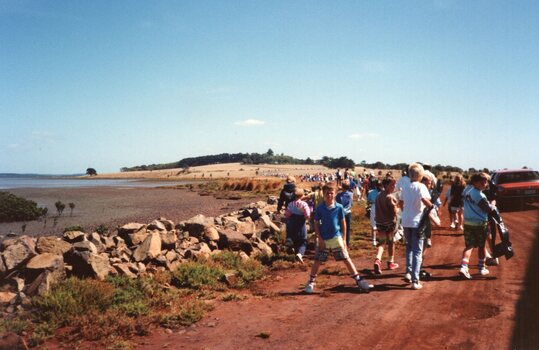 Photograph of people walking on dirt road