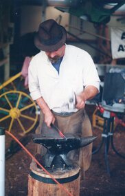 a photograph of man blacksmithing