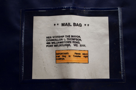  Photo of a Port Melbourne City Council Mail Bag, with the request for the bag to be returned by Tuesday night highlighted in orange.  