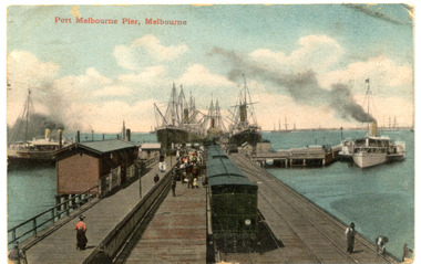   Hand Coloured postcard of a railway pier with ships docked around the pier.
