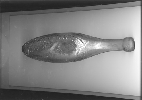 Glass bottle with round pointed bottom and moulded lettering.