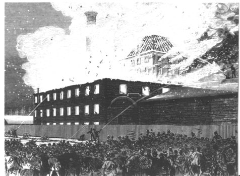 A large crowd watches relatively few firemen aim their hoses at a well established fire in a factory complex.
