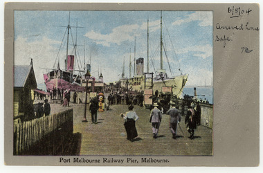 Four people walk towards a very crowded section of a pier where two ships are berthed.
