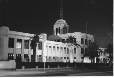 Substantial two storey building with a central tower floodlit at night.