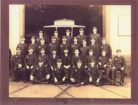 Twenty-seven men in uniform posing in four rows at the entrance to a building.