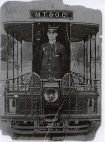 A man in uniform stands at the front of a cable tram.