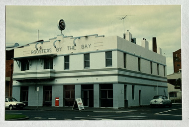 Two-storey hotel, Roosters by the Bay, on a street corner.