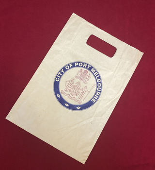 A brown paper bag with the City of Port Melbourne crest printed in blue and red.