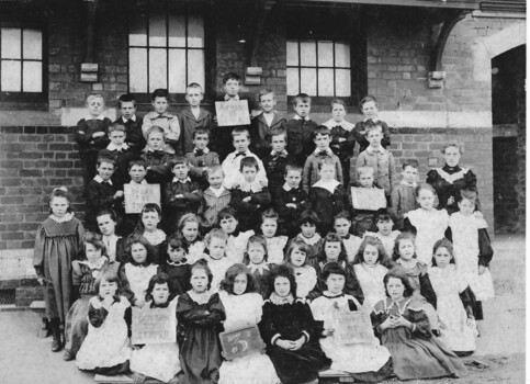 Fifty-three children pose for a class photo with their female teacher.