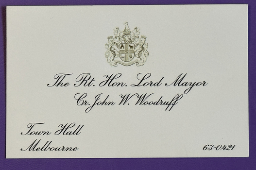 Cream coloured business card with crest of the City of Melbourne and details relating to Cr John W Woodruff, Mayor.