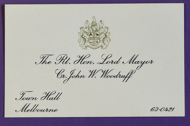 Cream coloured business card with crest of the City of Melbourne and details relating to Cr John W Woodruff, Mayor.