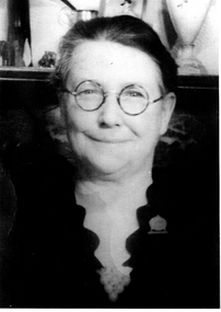 Head shot of a women wearing round glasses smiling towards the camera.