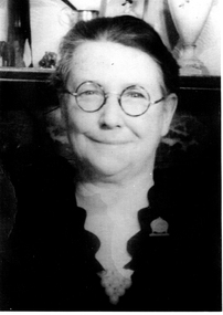 Head shot of a women wearing round glasses smiling towards the camera.