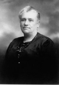 A photograph of the upper body and head of a woman wearing a black dress.