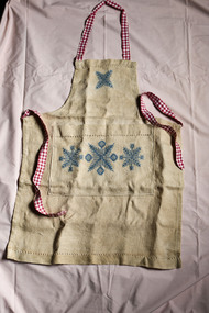 Old wash apron made from a bleached hessian (onion or potato) bag, pink & white gingham ties and a blue pattern stencil on the front of the apron.
