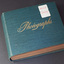 A thick photograph album with a blue cover with two small white stickers with "MELB" on one and "DOCKS" on the other handwritten in red 