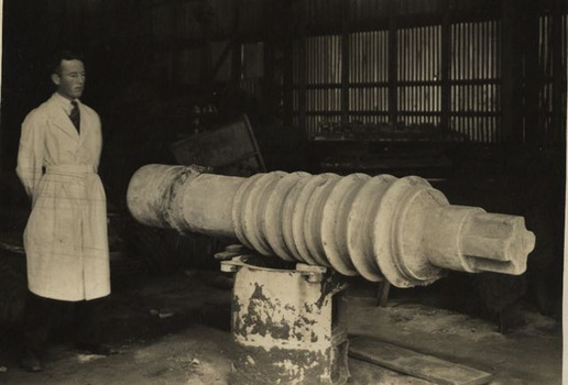 Black & white photo of a gentleman standing along a piece of equipment.