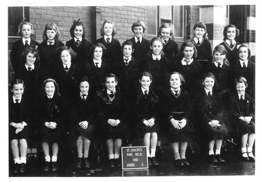 Black & white photo of school girls poising for class photo.