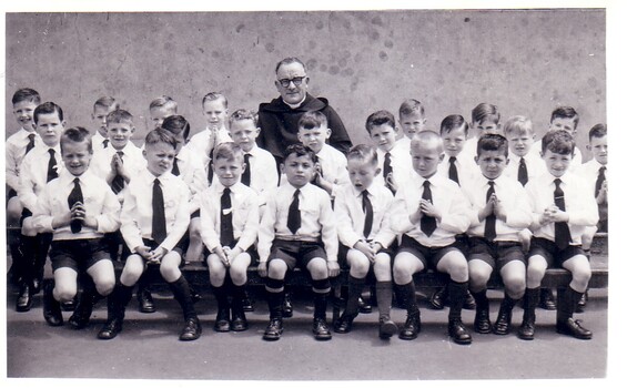 Black & white photo of school boys dressed in uniform oping for their class photo.