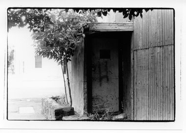Black & white photo of an entrance into a derelict building.