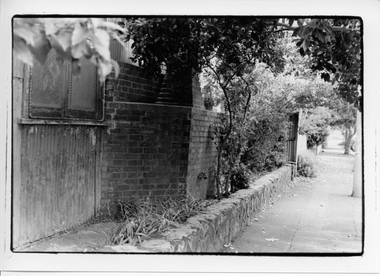 Black & white photo of a building and tree lined footpath.