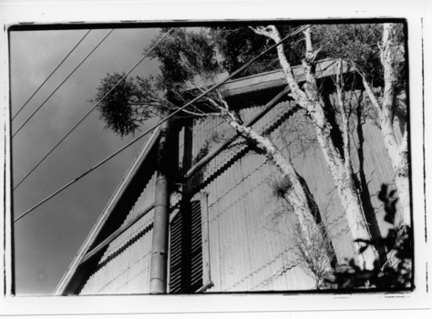 Black & white image of a side view of a corrugated iron building.