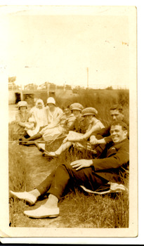Group of people sitting on grass land.