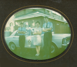 2313 - Gladys Coghlan and two policemen in front of police car at Port Melbourne Police Station in 1960s