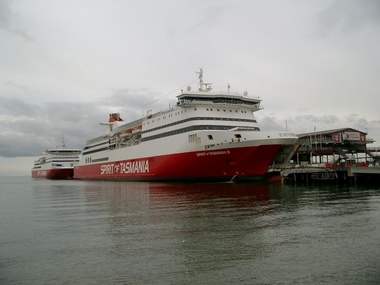 Two ships berthed at a large pier.