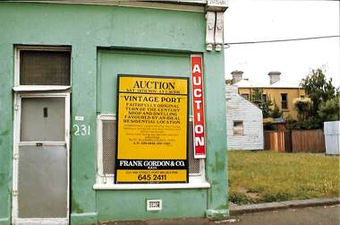 Small green house with a large yellow auction sign with the heading "Vintage Port".