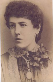 Photo of a lady dressed in early 1900 century clothing wearing a large locket around her neck.