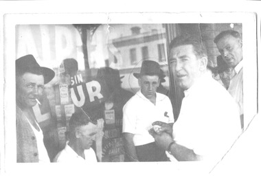 A close view of a group of men in front of a shop window.