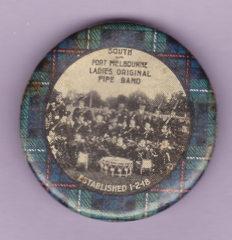 A round badge with a black and white photograph of the South and Port Melbourne Ladies Original Pipe Band, established 1 Feb 1918 surrounded by McKenzie and Stuart tartan.
