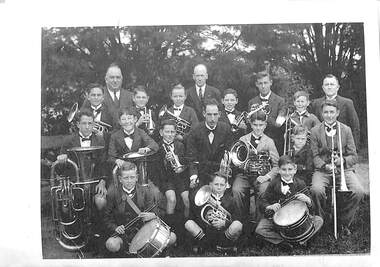 Photograph of boys with musical instruments and a few men posed in four rows.