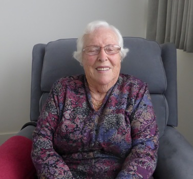 A woman sitting face on in an armchair.