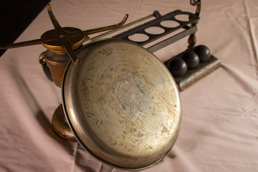 A set of manual scales with the pan leading against the base showing many signatures on the bottom.